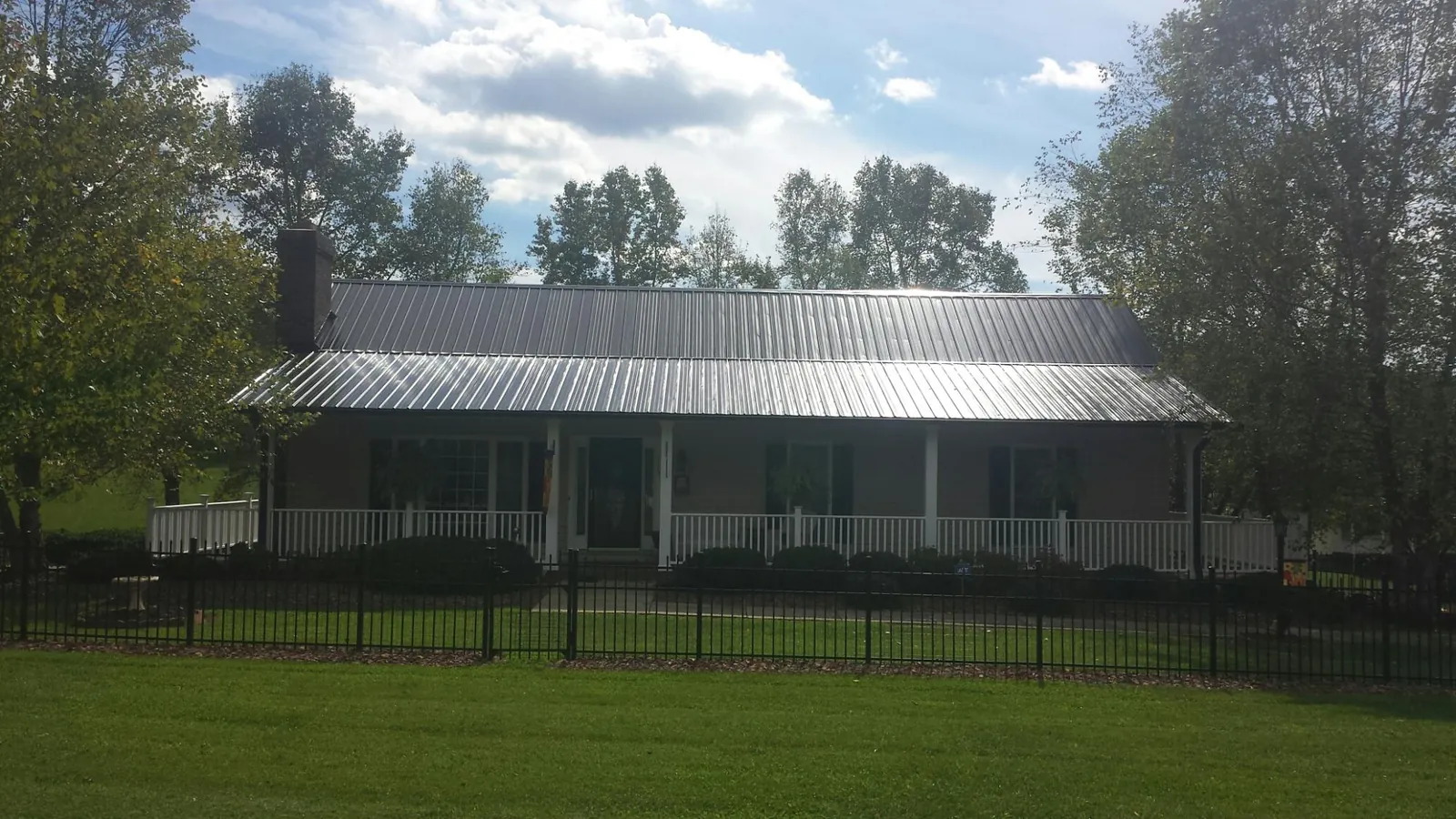 Gray metal roof on a brick ranch with a full width front porch — Gutter Guard Installation work by our crew in Maquoketa