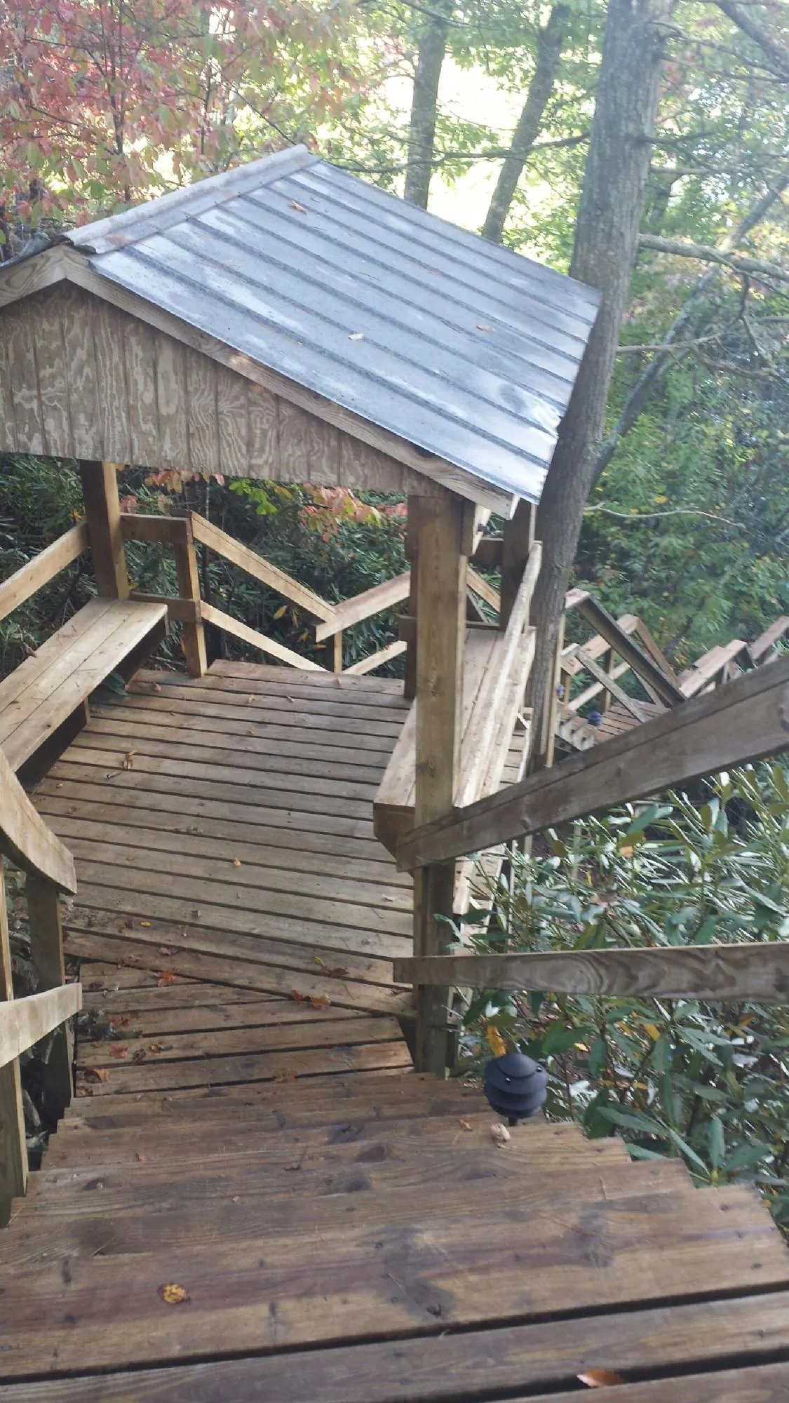 Metal roofed shelter over wooden steps on a wooded walkway — Skylight Repair & Installation work by our crew in Maquoketa