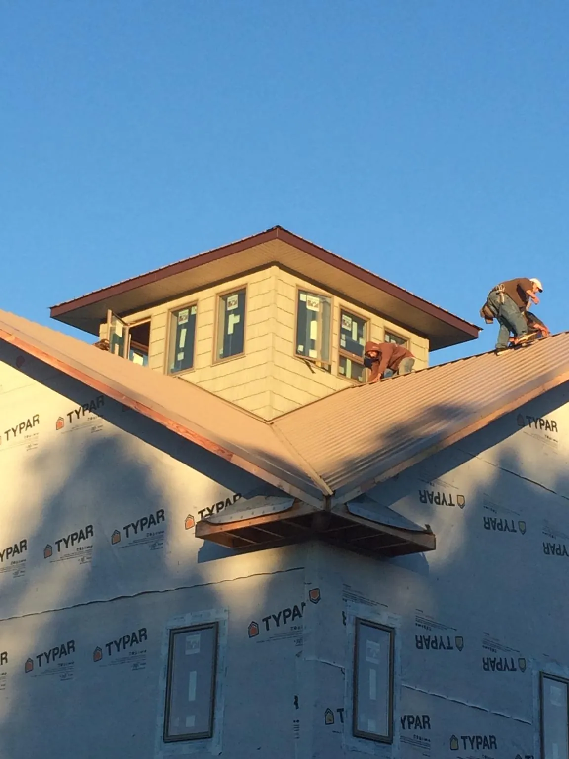 Roofers working around a rooftop cupola on a new metal roof at sunset — Roof Waterproofing in Maquoketa by Roofing Brothers
